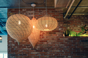 Wooden weave lamp hanging on ceiling and brick wall