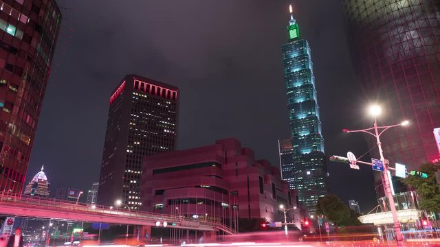4K night time lapse of a busy street corner in Downtown Taipei City at rush hour with cars & buses dashing by, Taipei 101 Tower & World Trade Center Building in Xinyi Fina