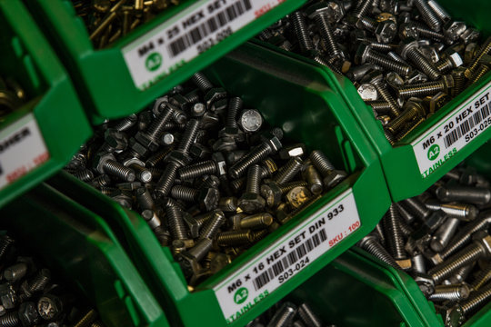 Hundereds of bolts and nuts of various shapes and sizes in green tubs located in a london factory. Used for industrial and commercial production shiny new hardware.