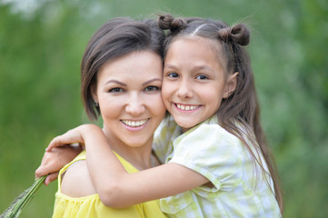 Portrait of young mother and daughter hugging in autumn park