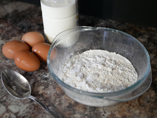 flour, eggs, milk. Baking ingredients. Spoon on a marble table. Preparation for cooking.
