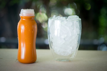 Thai milk tea in plastic bottle served with ice in glass on wood table