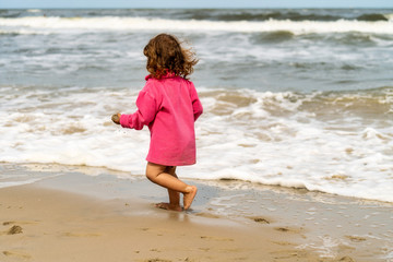 kleines Mädchen rennt am Strand entlang