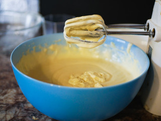Beat the dough in a bowl. dough with a mixer. Blue plate. the dough hangs from the mixer.