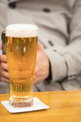 Chilled glass of light beer with men in sweater background