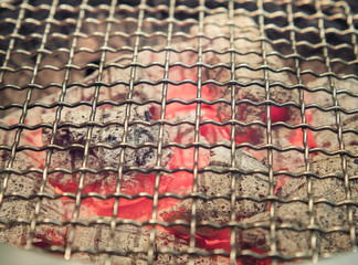 Steel grate for grilling food on hot charcoal, Close up and selective focus of flammable charcoal in fire red.