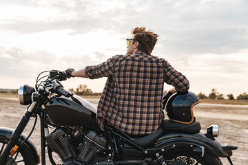 Young man biker on bike outdoors at the desert field.