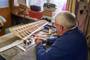 Senior man makes the wing of a radio-controlled aircraft, the construction of the airplane, back...