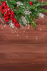 Christmas background. New Year fir tree, dog rose, fresh leaves and artificial snow. Wooden boards backdrop