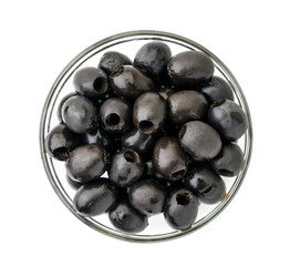 Black olives in a glass plate on a white. The view of the top.