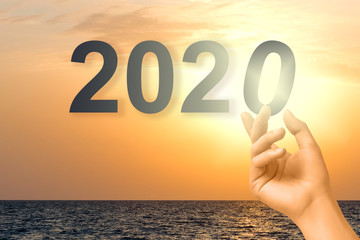 The concept of the beginning of the new 2020 inscription on the background of the sea. The girl...