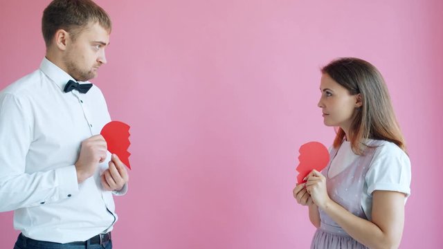 Slow Motion Of Couple Dividing Heart Shape Valentine And Walking Apart Holding Halves. Romantic Relationship, Separation And Tender Feelings Concept.