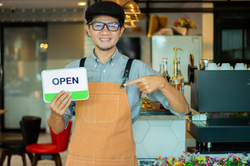small business owner standing with coffee machine in his own coffee shop holding cup of coffee.man holding an opening sign while opening