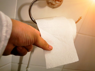 A Hand holding toilet paper in the toilet