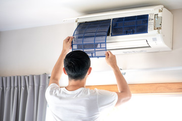 Technician man repairing ,cleaning and maintenance Air conditioner on the wall in bedroom.On site home service,Business ,Industrial concept.