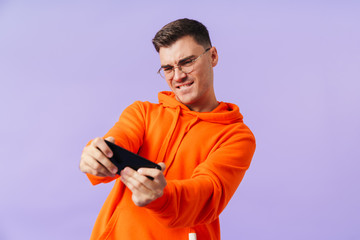 Fototapeta premium Emotional concentrated young man play games by mobile phone.