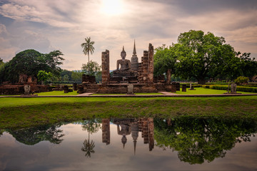 Fototapeta na wymiar Ancient Buddha statue at Wat Mahatat with sunset sky. Sukhothai Historical Park, UNESCO world heritage.