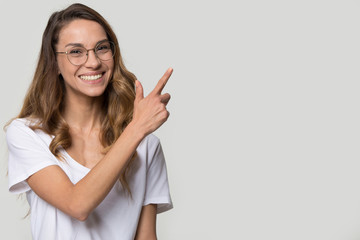 Happy young woman wearing glasses pointing finger at copy space
