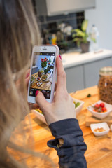 Woman with red nails shooting photos of food on a household table with her mobile phone for social media instagram healthy diet high protein food for a great body and lifestyle
