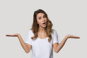 Fototapeta premium Confused attractive young woman shrugging shoulders, looking at camera