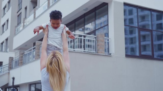 Young interracial family, mom and son. A young mother is spinning her son in her arms on a summer evening.