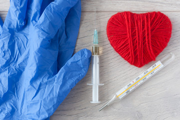 The syringe and red heart on white wooden background
