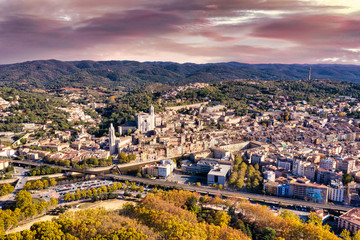 Aerial view of the Spanish city of Girona. Sunset sky, houses, streets, city park and roads. - 306196456