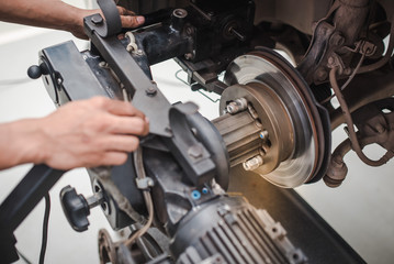 Fototapeta na wymiar Brake disc grinding machine - Vehicle brake-disc turning machine. Automobile disc brake system repair in garage.