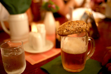a sesame bun lies on top of a beer in a pub
