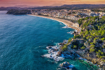 Spanish resort town of Lloret de Mar located in Costa Brava is a coastal region of Catalonia. Aerial view. Sant Joan Castle, sea, sunset. - 306196875