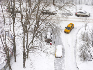 Winter. Top view of the road in residential courtyard of the city. Cars in parking are covered...