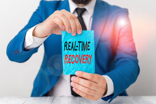 Conceptual hand writing showing Real Time Recovery. Concept meaning maximum time period in which recent data can recover Man holds empty paper with copy space in front of him Space