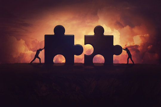 Two determined businessman pushing big jigsaw puzzle pieces to unite and complete the purpose. Business teamwork concept, achieving success together by joining forces. Group cooperation process.