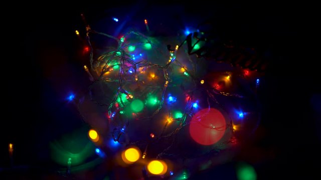 Beautiful colored LED lights draw cycles on the image while a hand places and removes a sign in which you can read Merry Christmas in Spanish. Feliz Navidad