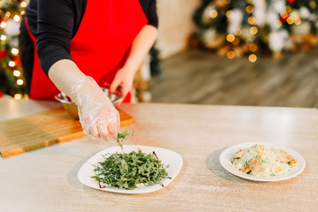 New Year 2020. Christmas table dinner time with salad decorated in New Year style on bokeh background. Christmas beautiful lights on gold warm background. Preparation of Caesar salad.
