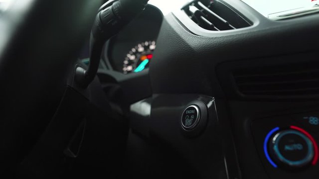 Male hand pushes engine start stop button in a modern car interior