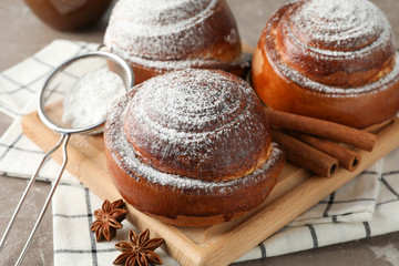 Tasty cinnamon roll with ingredients, coffee on brown table against blue background, closeup. Top view