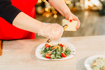 New Year 2020. Christmas table dinner time with salad decorated in New Year style on bokeh background. Christmas beautiful lights on gold warm background. Preparation of Caesar salad.