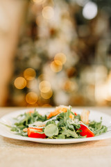 New Year 2020. Christmas table dinner time with salad decorated in New Year style on bokeh background. Christmas beautiful lights on gold warm background.