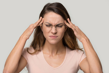 Unhappy woman wearing glasses touching temples, relieving headache
