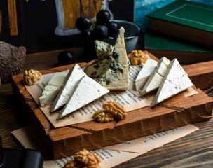 Naklejka na ściany i meble wooden board of different cheeses and walnuts