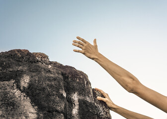 Hand reaching out for help up mountain cliff. 