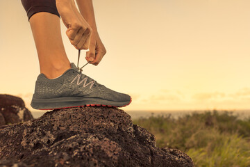 Runner tying her shoe laces early morning. Exercise and active lifestyle concept. 