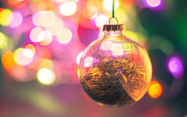 Colourful Christmas lights bokeh background with a see-through glass globe 