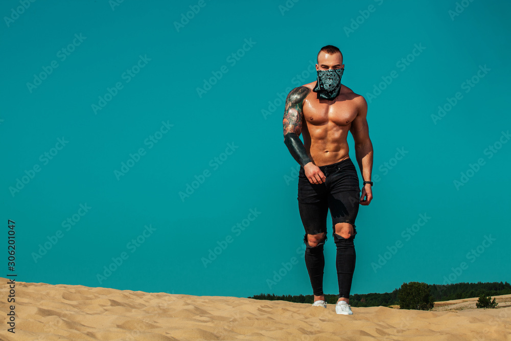 Wall mural Sportsmen men, fit athlete are standing on the sky background at desert. Healthy lifestyle and sport. Fitness concept.