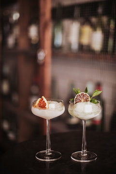 Two gin based sorbet cocktails on a silver table. Concept of refreshing cocktails and alcoholic drinks. Selective focus on the glasses.