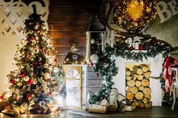 New Year 2018. Christmas beautiful lights on gold warm background. Tree, toys. Photo of interior of room with a wooden wall, wreath and garlands, fireplace with firewood. The letters from foam plastic