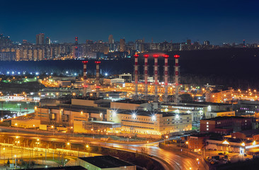 Night view from a height of a large city power station against the backdrop of the cityscape