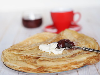 thin pancakes with tea and jam on the table