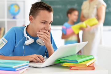 Portrait of cute boy using laptop in class room